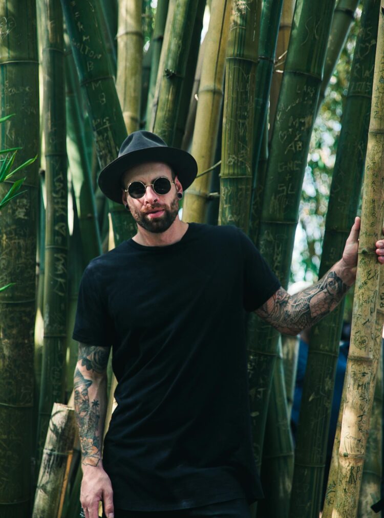 Man Holding Bamboo Plant Wearing Sunglasses and Fedora Hat